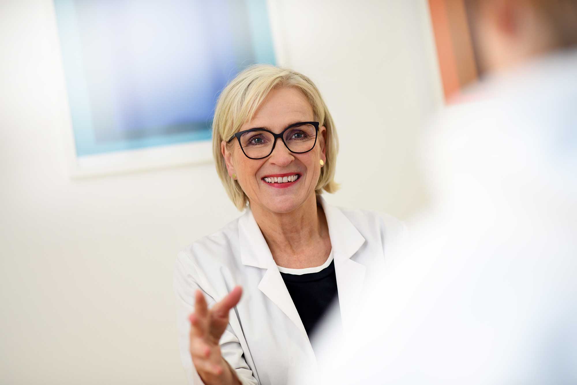 Ärztin im Gespräch, lächelt den Patienten an